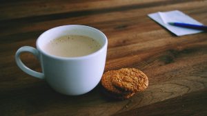 Uitnodigende koffietas en notitieblok op een donkere houten tafel